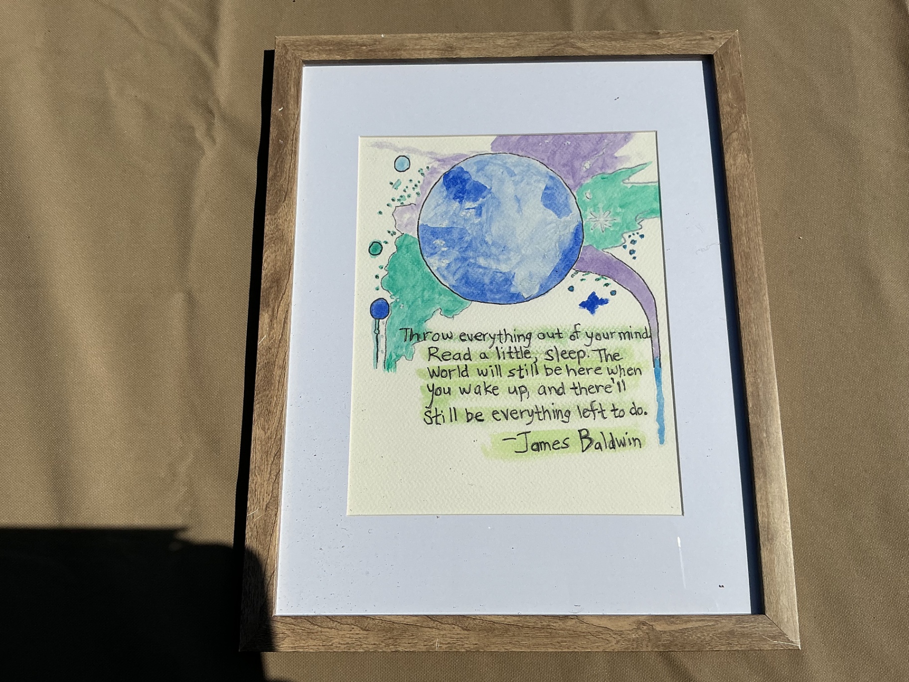 Watercolour quote piece with a James Baldwin text beneath a blue planet