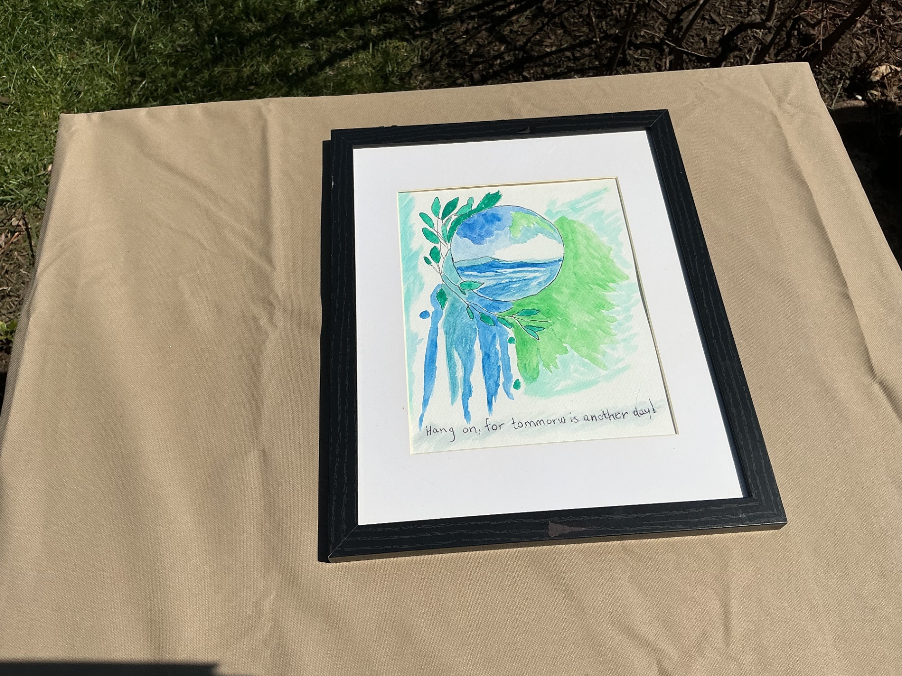 Watercolour of a blue-green orb with leaves and dripping paint above a handwritten hopeful phrase